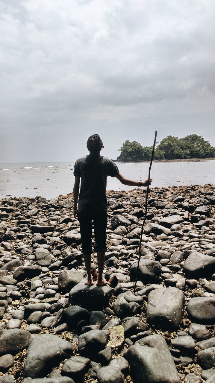 sky, water, rear view, sea, lifestyles, standing, full length, leisure activity, tranquility, casual clothing, cloud - sky, tranquil scene, beach, horizon over water, beauty in nature, scenics, nature, shore