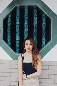 Portrait of woman standing against wall