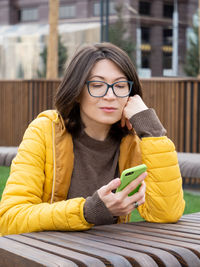 Woman in eyeglasses is reading news or messages on her smartphone. using wireless technologies.