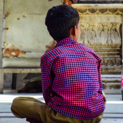 Rear view of boy sitting outdoors