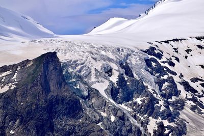 Scenic view of glacier and snowcapped mountains against sky