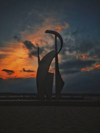 Silhouette structure by sea against sky during sunset