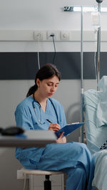 Young woman using mobile phone while sitting at clinic