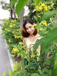 Portrait of woman standing by blooming flowers