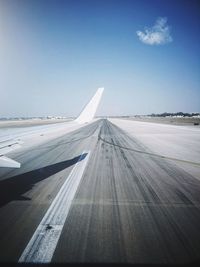 Airplane on airport runway against blue sky