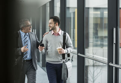 Two businessmen walking and talking on office floor