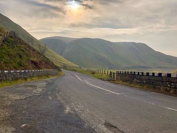 Road leading towards mountains against sky