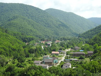 Houses by trees and mountains against sky