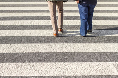Low section of people walking on zebra crossing