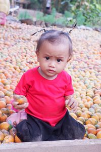 Portrait of cute girl sitting on fruits