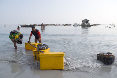 People working in sea against clear sky