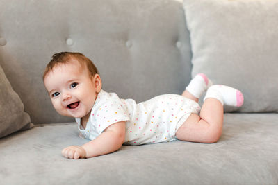 Happy baby lying on sofa and looking at camera at home