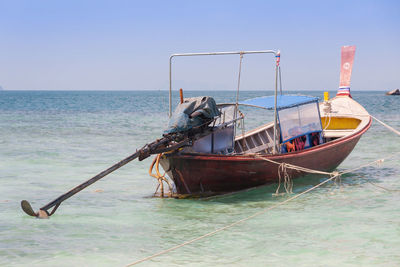 Fishing boat moored in sea against clear sky