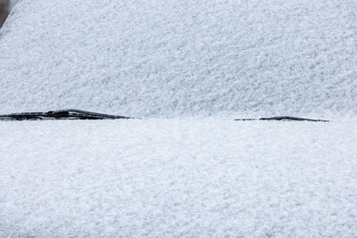 Snow covered car windshield, wipers and bonnet