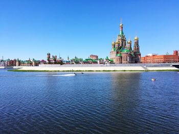 View of river by buildings against blue sky