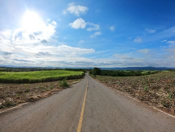 Road amidst field against sky
