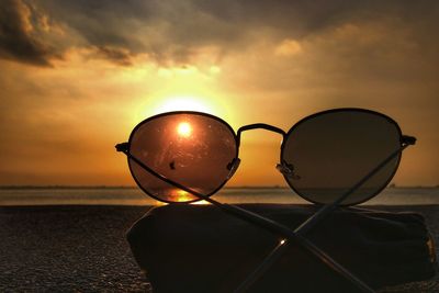 Close-up of sunglasses against sky during sunset