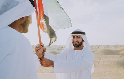 Happy young man holding woman standing against the sky