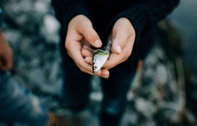 Young boy holding his first fish catch whilst fishing with family