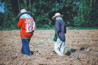 Rear view of boys working on field