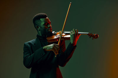 Man playing violin against black background