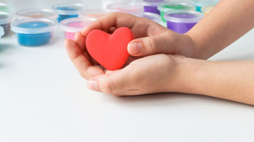 Close-up of woman holding heart shape on table