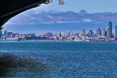 Sea by buildings against sky in city