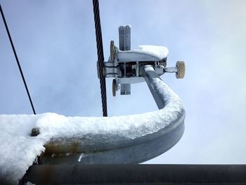 Low angle view of detachable chairlift grip against sky during winter