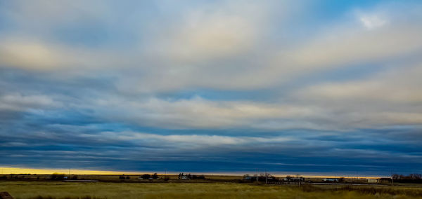 Scenic view of field against cloudy sky