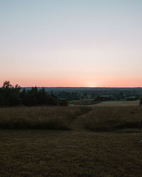 Scenic view of field against clear sky during sunset