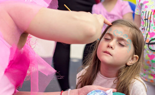 Midsection of woman applying face paint to girl