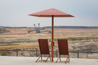 Empty chairs on field against clear sky