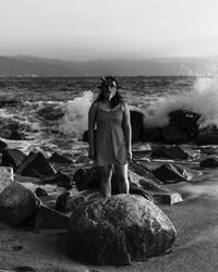 Rear view of woman standing on beach against clear sky