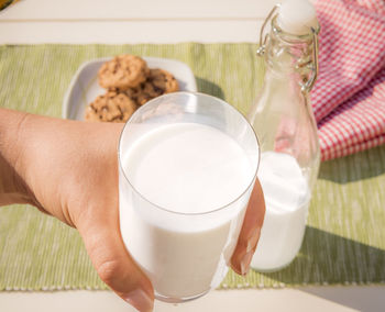 High angle view of hand holding glass of milk