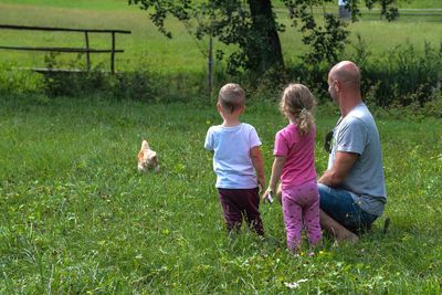 Siblings with father on grassy field