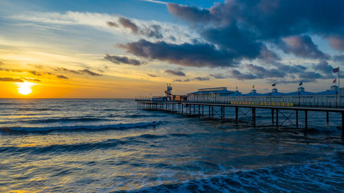 Pier over sea against sky during sunset