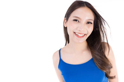 Portrait of smiling young woman against white background