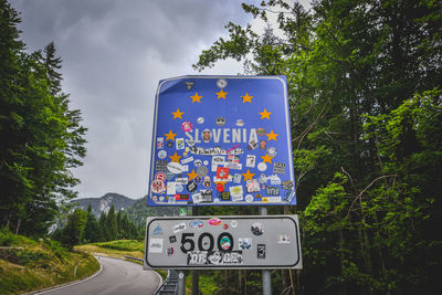 Information sign by road against sky