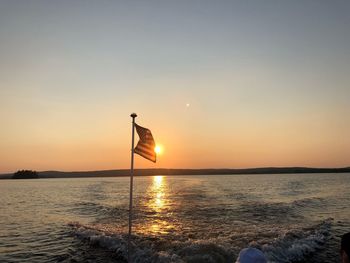 Silhouette person in sea against sky during sunset