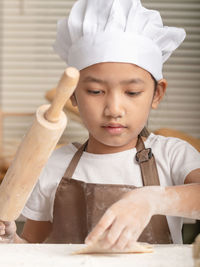 Close-up of girl holding rolling pin preparing food at kitchen