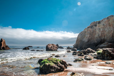 Rock formation in sea against blue sky