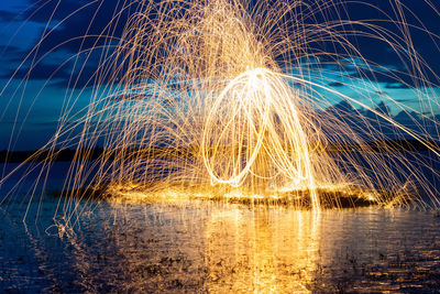 Wire wool over river against sky at night