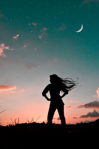 Silhouette woman standing on field against sky during night