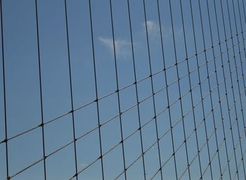 Low angle view of metallic fence against sky