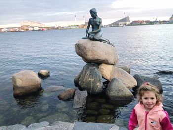 Statue by river against sky