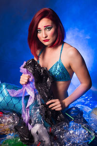 Portrait of beautiful young woman sitting in swimming pool