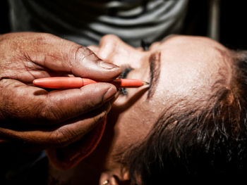 Cropped hand of beautician applying eye make-up to customer