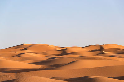 Sand dunes in desert against clear sky