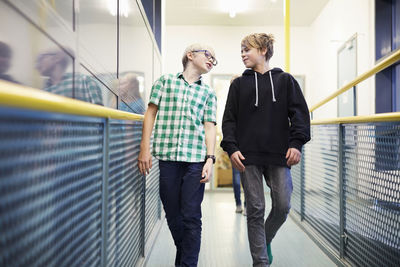 Boy talking with male friend while walking in school corridor