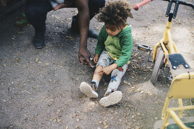 High angle view of son showing bruise to father while sitting by tricycle at park